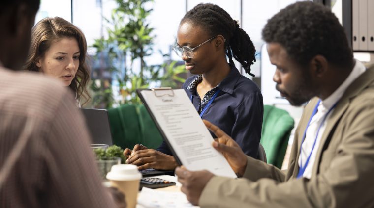 Forecast affiliates collaborating in a high end workspace to determine resource allocation plan for project success, utilizing smart technology and infographics to present data driven insights.