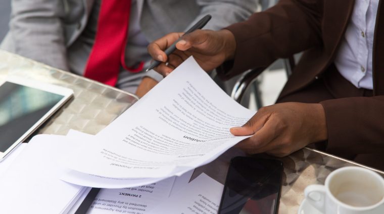 Businessman consulting legal expert in coffee shop. Closeup of business man and woman sitting in cafe and reading documents. Paperwork concept
