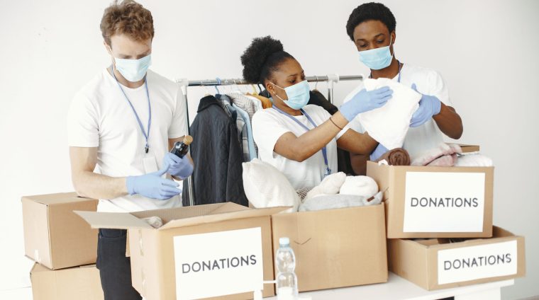 Guy and girl with check boxes. Volunteers in masks. Boxes with humanitarian aid.