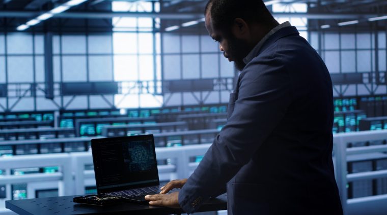 Software developer in data center using artificial intelligence computing simulating human brain. IT support staff member working on notebook with AI machine learning algorithms, camera A